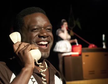 Fenton in foreground talking on white phone, Mistress Quickly in blurred background wearing maids dress talking on phone