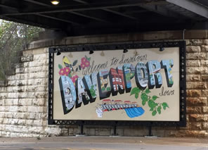 Photo of a sign on a stone wall under metal bridge